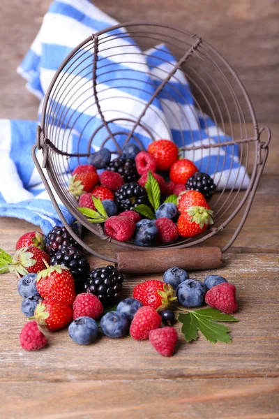 成熟甜的不同的莓果在金属的篮子里，旧的木制的桌子上 — 图库照片