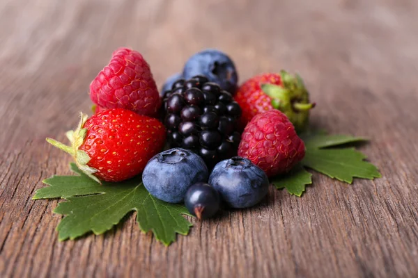 Ripe sweet different berries, on old wooden table — Stock Photo, Image