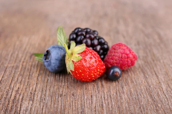 Ripe sweet different berries, on old wooden table — Stock Photo, Image