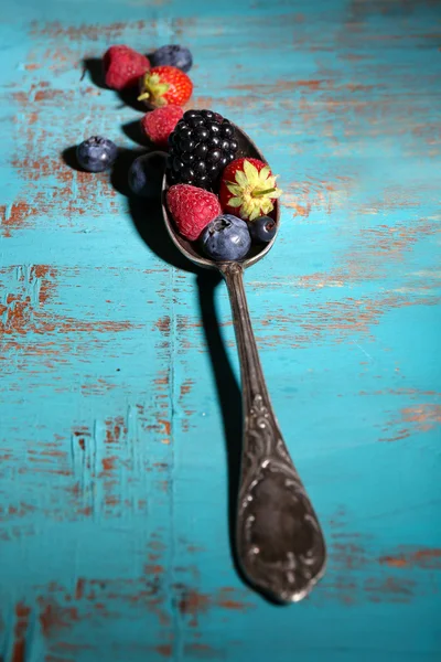 Bayas maduras dulces diferentes en cuchara vintage, sobre mesa de madera vieja —  Fotos de Stock