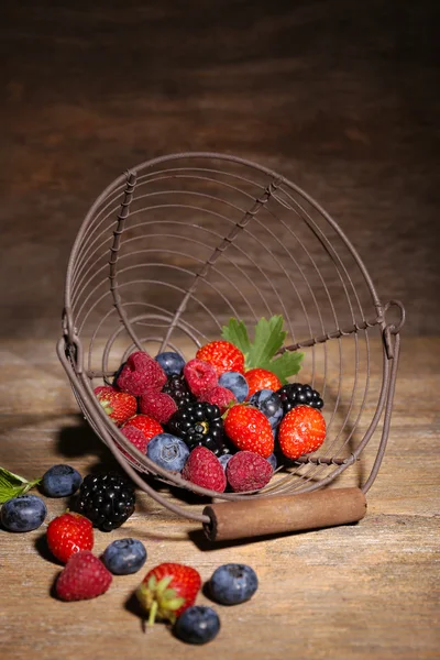 成熟甜的不同的莓果在金属的篮子里，旧的木制的桌子上 — 图库照片