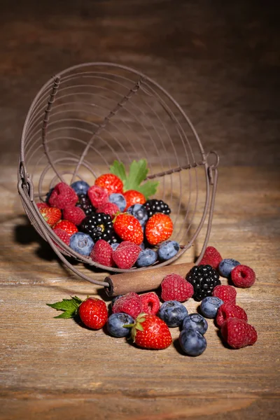 Ripe sweet different berries in metal basket, on old wooden table — Stock Photo, Image