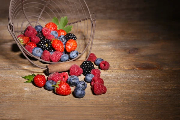 Ripe sweet different berries in metal basket, on old wooden table — Stock Photo, Image