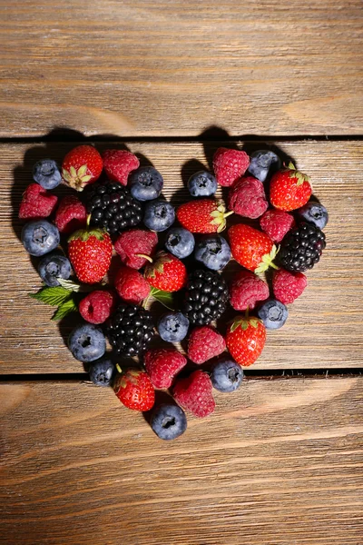 Heart of ripe sweet different berries, on old wooden table — Stock Photo, Image