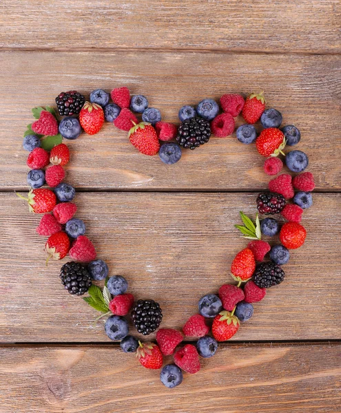 Heart of ripe sweet different berries, on old wooden table — Stock Photo, Image