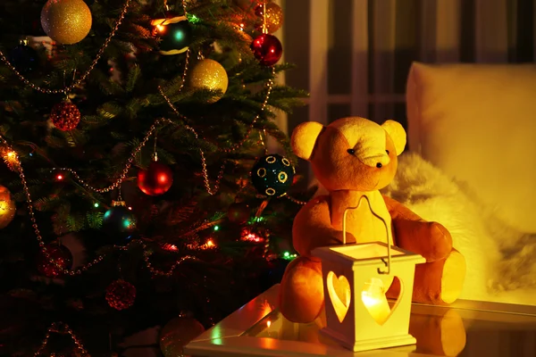 Urso de pelúcia em casa interior na árvore de Natal decorada fundo — Fotografia de Stock