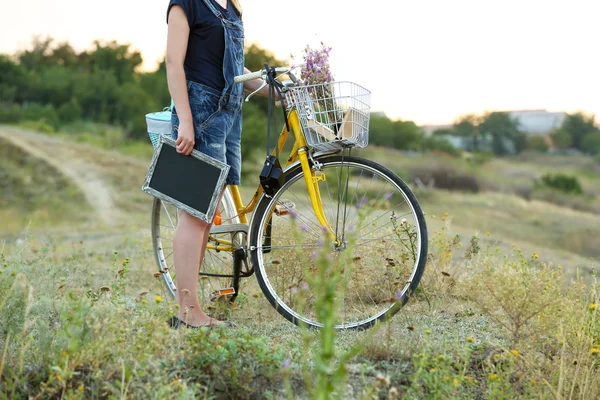 Mujer joven con bicicleta en el prado — Foto de Stock