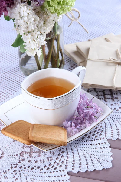 Composição com xícara de chá, cartas antigas e belas flores de primavera em vaso, na mesa de madeira, no fundo brilhante — Fotografia de Stock