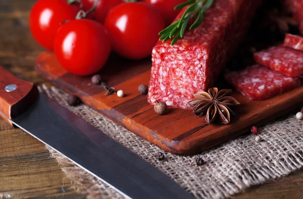 Leckere Salamiwurst und Gewürze auf Holzgrund — Stockfoto