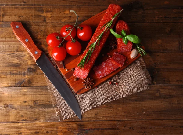 Salsicha de salame saboroso e especiarias em fundo de madeira — Fotografia de Stock