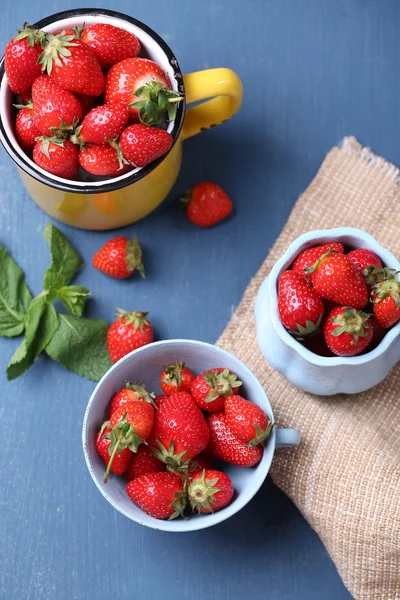 Mogna söta jordgubbar i mugg på färg trä bakgrund — Stockfoto