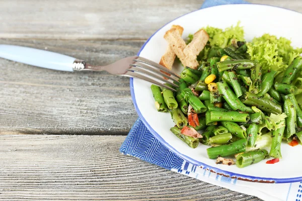 Salade met groene bonen, ham en maïs op plaat, op een houten achtergrond kleur — Stockfoto