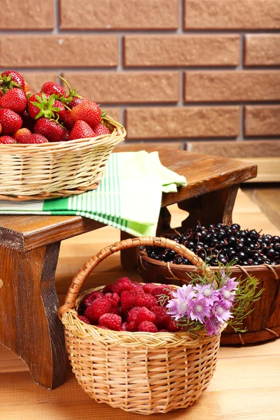 Fresh berries in baskets on wall background — Stock Photo, Image