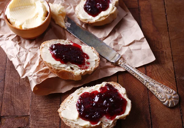 Frisches Brot mit hausgemachter Butter und schwarzer Johannisbeermarmelade auf Holzgrund — Stockfoto