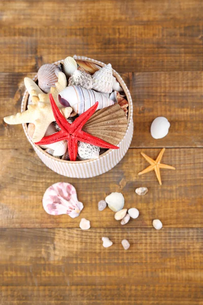 White box full of sea gifts on brown wooden background — Stock Photo, Image