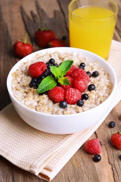 Tasty oatmeal with berries on table close-up — Stock Photo, Image