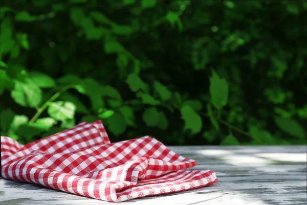 Wooden table with tablecloth, outdoors — Stock Photo, Image