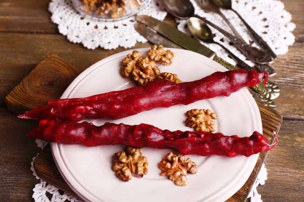 Sabrosos dulces orientales (churchkhela) y nueces frescas, sobre fondo de madera — Foto de Stock