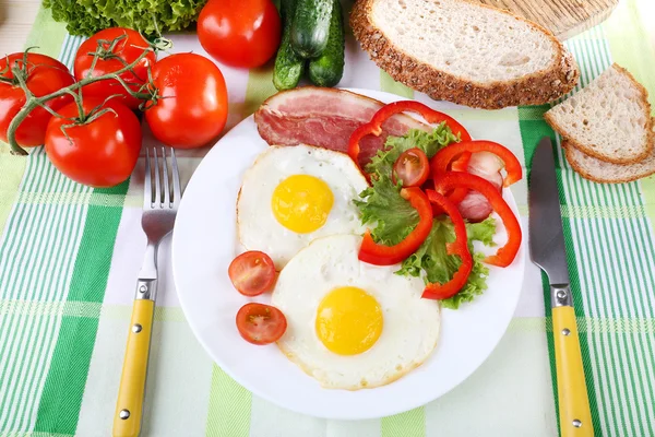 Scrambled eggs with bacon and vegetables served on plate on fabric background — Stock Photo, Image