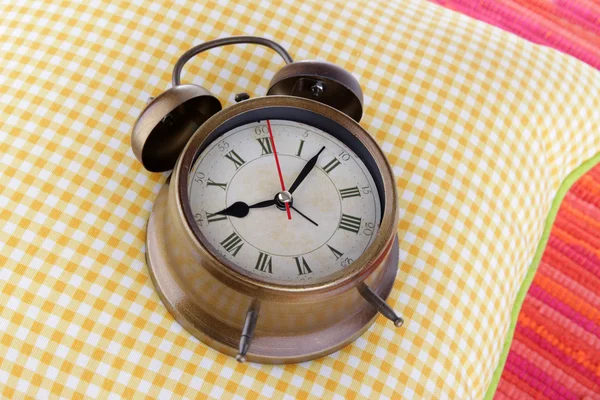 Metal clock on a yellow pillow on red background — Stock Photo, Image