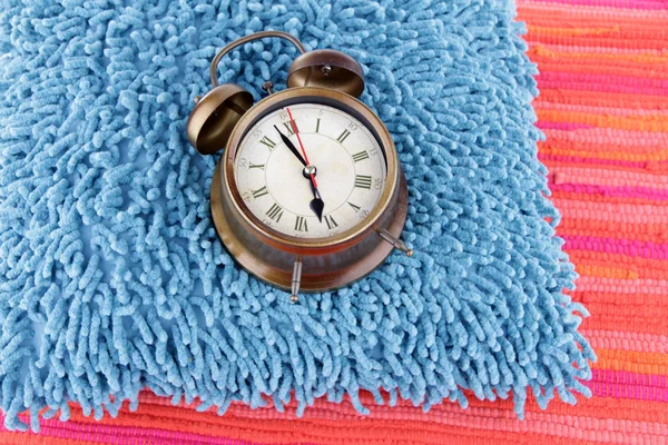 Metal clock on a blue pillow on red background — Stock Photo, Image