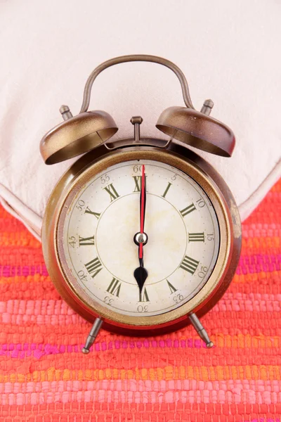 Metal clock on a white pillow on red background — Stock Photo, Image