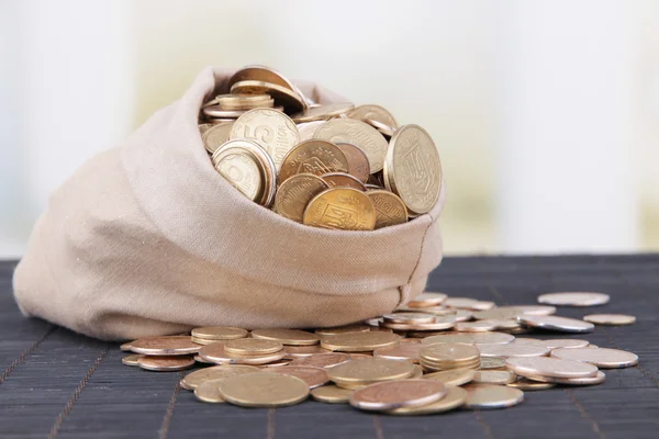 Fabric bag full of Ukrainian coins on wooden background — Stock Photo, Image