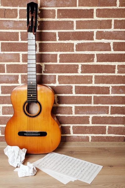 Guitarra no chão no fundo da parede de tijolo — Fotografia de Stock