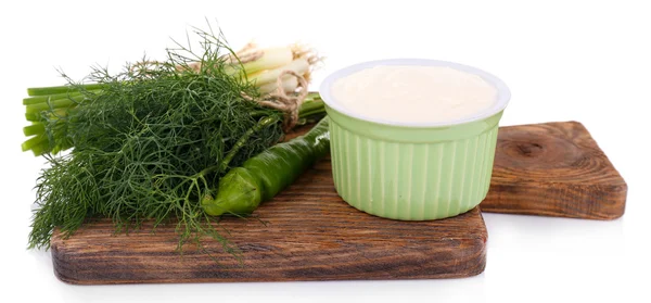 Kunststof ronde kom met room en peper, peterselie en dille in de buurt van het op een houten snijplank op witte achtergrond geïsoleerd — Stockfoto