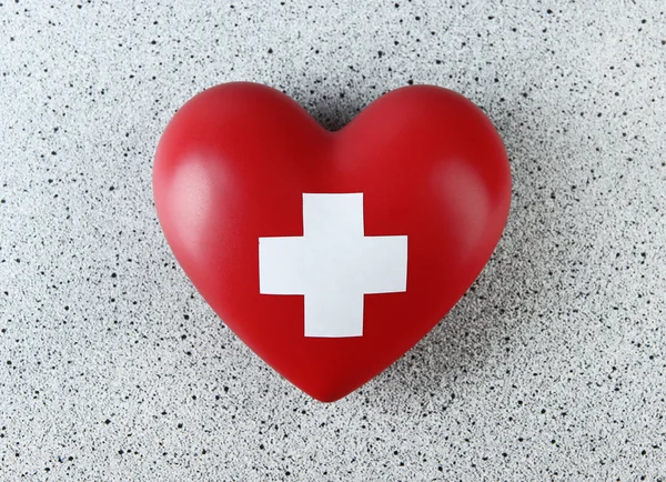 Red heart with cross sign on color background — Stock Photo, Image