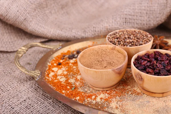 Round wooden bowl of seasoning and bay leaves on a metal round tray on  a piece of sacking — Stock Photo, Image