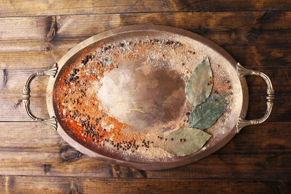 Vassoio rotondo in metallo con manici con condimento sparso e foglie di alloro su fondo di legno — Foto Stock