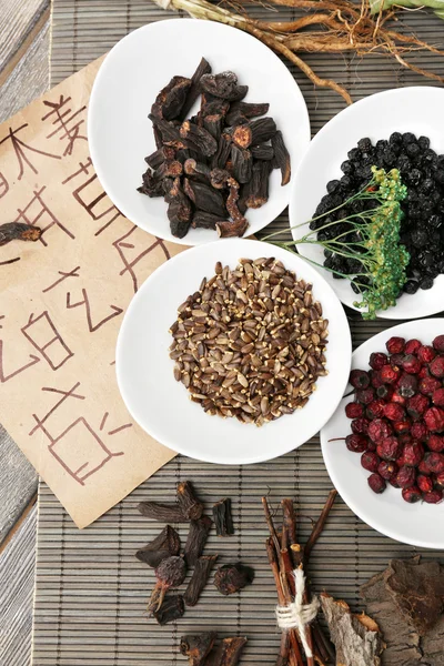Ingredientes tradicionais de ervas chinesas com hieróglifos não reais, close-up — Fotografia de Stock