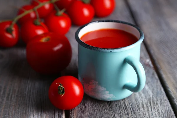 Jugo de tomate casero en taza de color y tomates frescos sobre fondo de madera —  Fotos de Stock