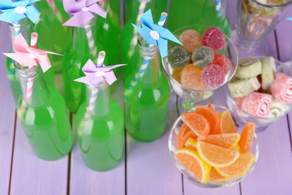 Botellas con bebida y dulces sobre fondo de madera — Foto de Stock