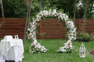 Beyaz, pembe çiçekler ve açık hava yeşilliği ile süslenmiş daire şeklinde düğün kemeri, kopyalama alanı. Düğün arka bahçede olacak. Çiçek bileşimi