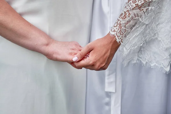 Mother and daughter holding hands on wedding day indoors, copy space