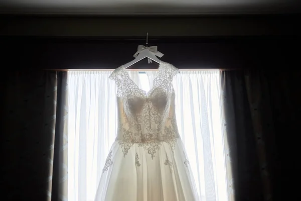 美丽的米色绣花婚纱挂在衣架上 靠在窗户上 复制空间 新娘早晨准备 — 图库照片