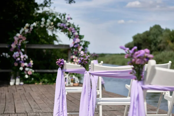 Білі Весільні Стільці Свіжими Квітами Фіолетовою Тканиною Кожного Боку Арки — стокове фото