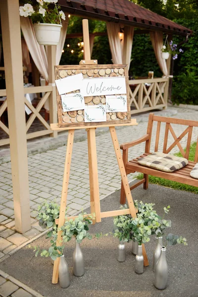 Wood easel with blank white board at wedding reception in restaurant, copy space. Table list or seating chart at wedding banquet. Welcome zone