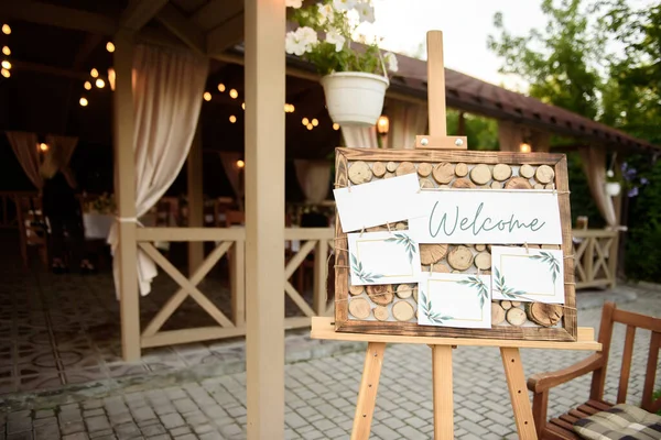 Wood easel with blank white board at wedding reception in restaurant, copy space. Table list or seating chart at wedding banquet. Welcome zone