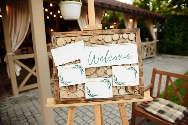 Wood easel with blank white board at wedding reception in restaurant, copy space. Table list or seating chart at wedding banquet. Welcome zone