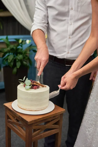 レストランで新鮮なラズベリーとシナモンで飾られたエレガントな結婚式のケーキをカット幸せな花嫁と新郎は スペースをコピーします 結婚式パーティー — ストック写真