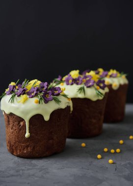 Mor çiçeklerle süslenmiş paskalya pastası ve koyu arkaplanda şekerler, kopyalama alanı. Mutlu Paskalyalar. Kulich 