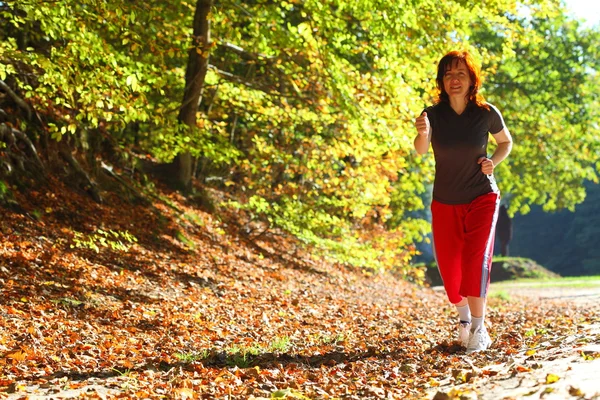 Woman walking cross country trail in autumn forest — Stock Photo, Image