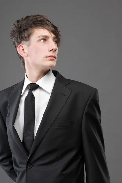 灰色の背景に青年実業家黒のスーツのカジュアルなネクタイ — ストック写真