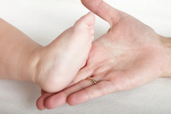 Pied bébé entre les mains de la mère — Photo