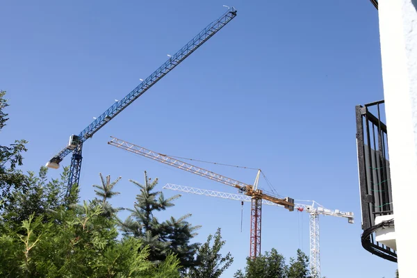 Construction cranes silhouetted against blue sky — Stock Photo, Image