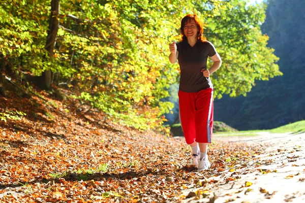 Vrouw lopen Kruis land parcours in herfst bos — Stockfoto