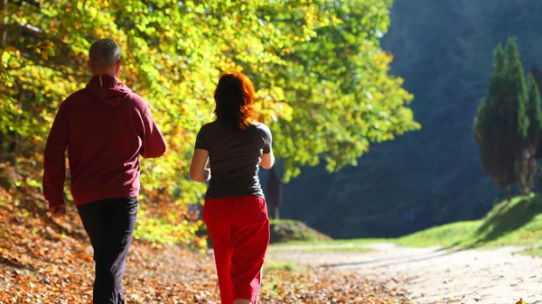 Kvinna och man terränglöpning vandringsled i höst skog — Stockfoto